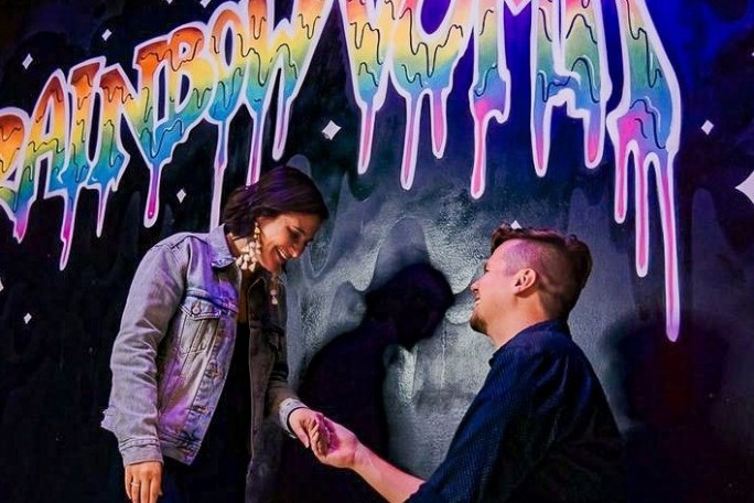 a group of people standing in front of a graffiti covered wall